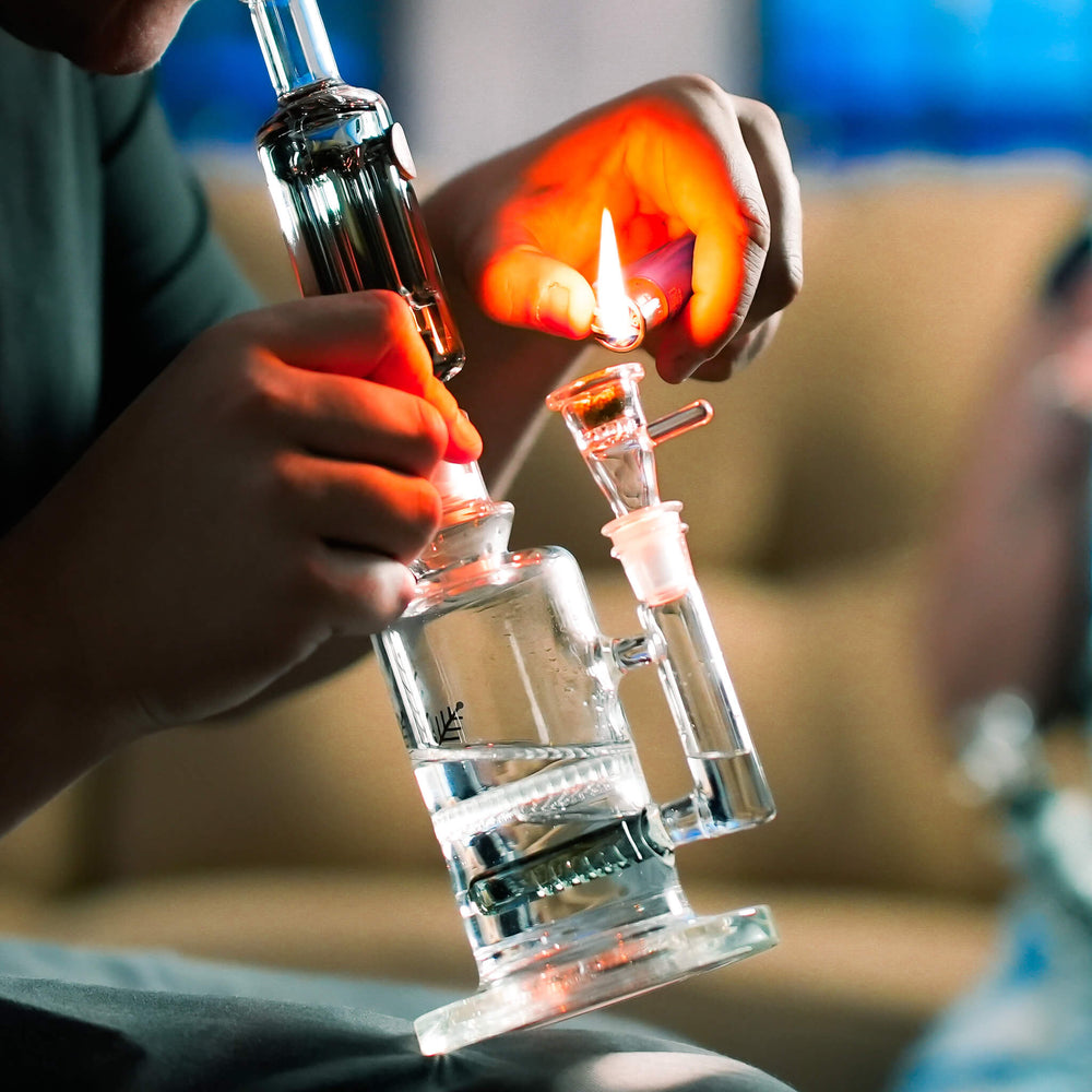 Lighting the bowl on a Mini Bong held in one hand, water moving through both percs
